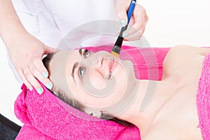 Woman esthetician applying mask beauty cream to pretty young girl