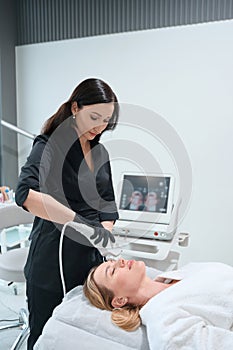 Woman esthetician performs hardware procedure for rejuvenating the frontal zone