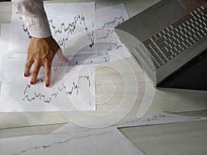 Woman examines charts of bitcoin at work table and computer