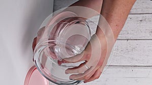 A woman examines glass food containers with plastic lids. Reviews the purchase. Containers of different sizes, stacked one on one