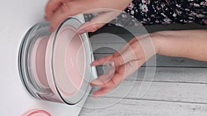 A woman examines glass food containers with plastic lids. Reviews the purchase. Containers of different sizes, stacked one on one