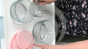 A woman examines glass food containers with plastic lids. Reviews the purchase. Vertical video