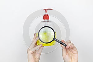 A woman examines the harmful components of liquid soap through a magnifying glass. Harmful composition of ingredients. Household