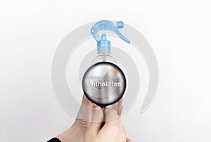 A woman examines the harmful ingredients of the air freshener through a magnifying glass. Means with phthalates. The concept of