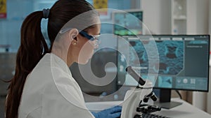 Woman examining dna sample on microscope tray in laboratory