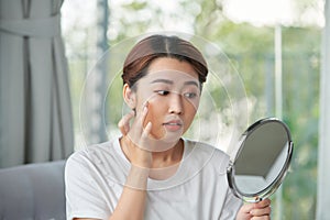 Woman examining her face in the mirror, problematic acne-prone skin concept