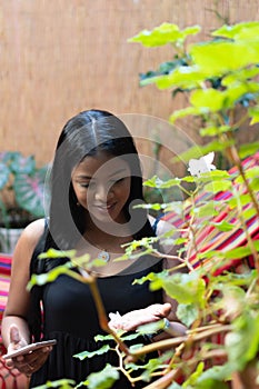 Woman examining plant by wall at home photo