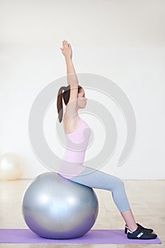 Woman, exercise ball and stretching with fitness, workout and wellness studio with equipment, gym and health. Profile