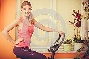 Woman on exercise bike listening music. Fitness