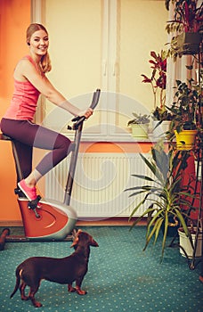Woman on exercise bike listening music. Fitness