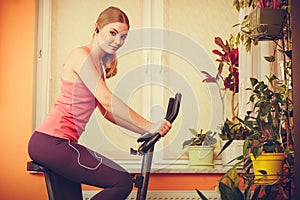 Woman on exercise bike listening music. Fitness