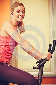 Woman on exercise bike listening music. Fitness