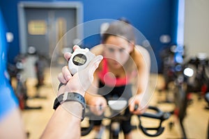 Woman on exercise bike with trainer timing her