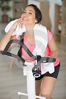 woman on exercise machine towelling off neck