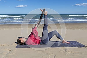 woman exercising on the beach with pilates ring