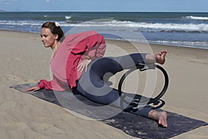 woman exercising on the beach with pilates ring