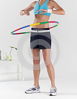 Woman exercising with colorful plastic hula hoop