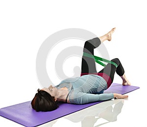 Woman exercising doing postnatal workout. Female fitness instructor working out with a rubber resistance band isolated on white