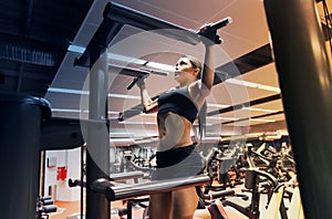 Woman exercising and doing pull-ups in gym