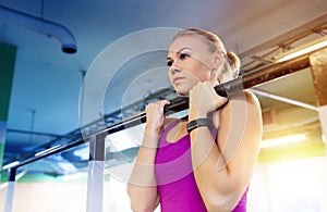 Woman exercising and doing pull-ups in gym