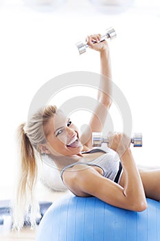 Woman exercising with dumbbells on a fitness ball