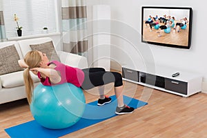 Woman Exercising With Fitness Ball While Watching Program