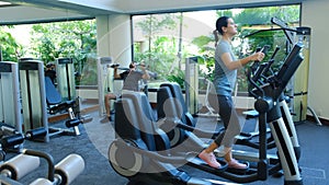 Woman exercising at the gym in an elliptical trainer. Young woman doing cardio training