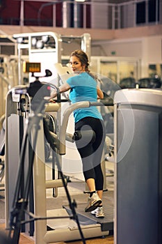 Woman exercising in gym with exercise-machine - leg day, wellbeing concept