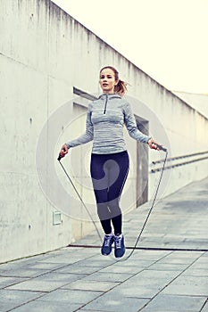 Woman exercising with jump-rope outdoors