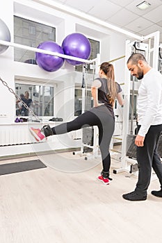 Woman exercising legs with personal trainer assist