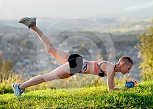 Woman exercising outdoors on the grass against city