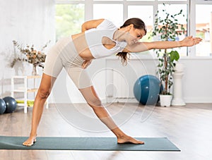 Woman exercising Revolved Triangle yoga pose Parivrtta Trikonasana in gym