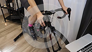 Woman is exercising on spin bike trainer. Female is cycling indoors on cycle trainer