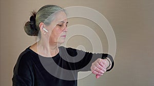 Woman exercising on treadmill. Gray hair female use wireless headphones.