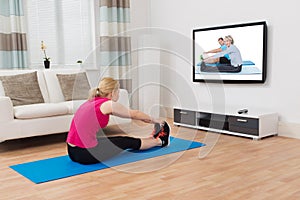 Woman Exercising While Watching Program On Television