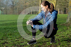 Woman Exercising In Winter Park Looking At Activity Tracker On Smart Watch