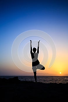 Woman exercising yoga sunset silhouette