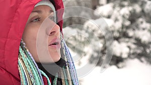 A woman exhales steam in the frosty air in winter. Portrait of an active woman in a winter cold day outdoors