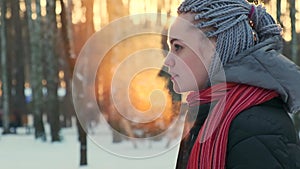 Woman exhales steam from her mouth in the winter at sunset. Super Slow Motion Side View of a Young Woman with Dreadlocks