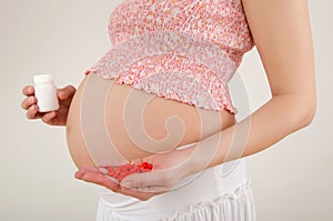 Woman expecting a baby holding pills in her hands.