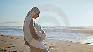 Woman expecting baby looking evening seascape standing beach. Pregnant girl