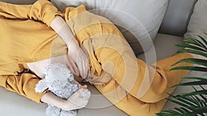 Woman expecting baby. Pregnant girl hugging belly and teddy bear toy resting, awaiting the child birth. Family planning