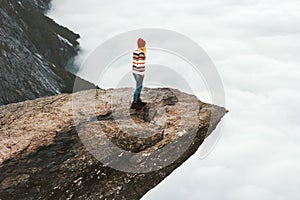 Woman explorer walking on Trolltunga rocky cliff in Norway