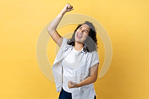 Woman expressing winning gesture with raised fists and screaming, celebrating victory.