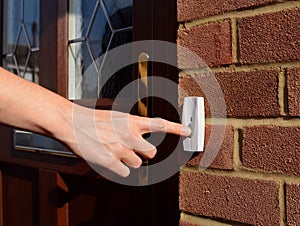 Woman extends her hand to ring doorbell photo