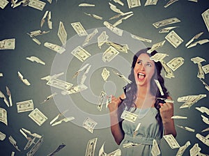 Woman exults pumping fists ecstatic celebrates success under money rain falling down dollar bills banknotes photo