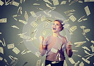 Woman exults pumping fists ecstatic celebrates success under money rain falling down dollar bills banknotes photo