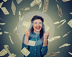 Woman exults pumping fists ecstatic celebrates success under money rain falling down dollar bills banknotes photo