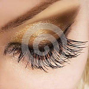 La mujer de los ojos extremadamente largas pestañas doradas y espejo de maquillaje.