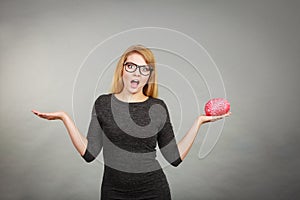 Woman in eyeglasses being confused holding brain